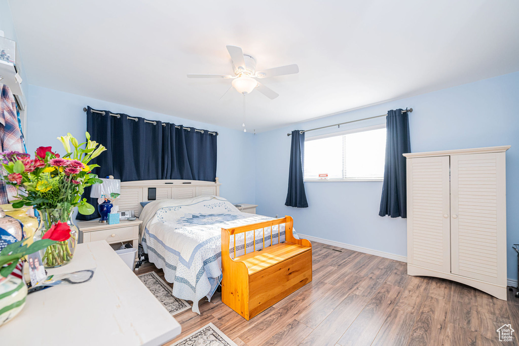 Bedroom with wood finished floors, baseboards, and a ceiling fan