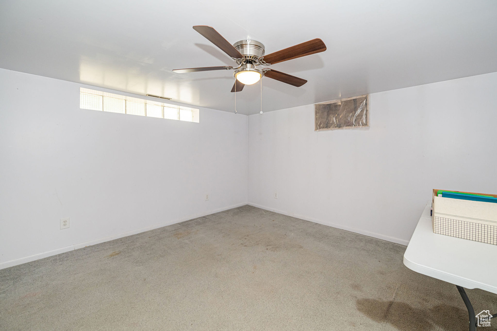 Carpeted empty room featuring ceiling fan and baseboards
