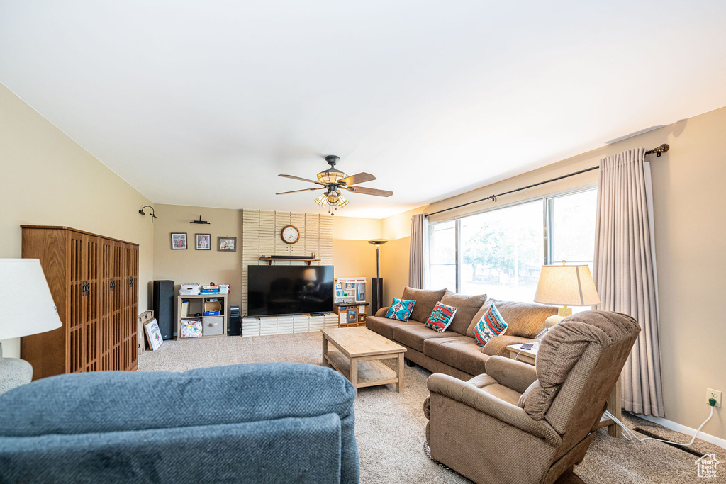 Living area featuring carpet flooring, a ceiling fan, and baseboards