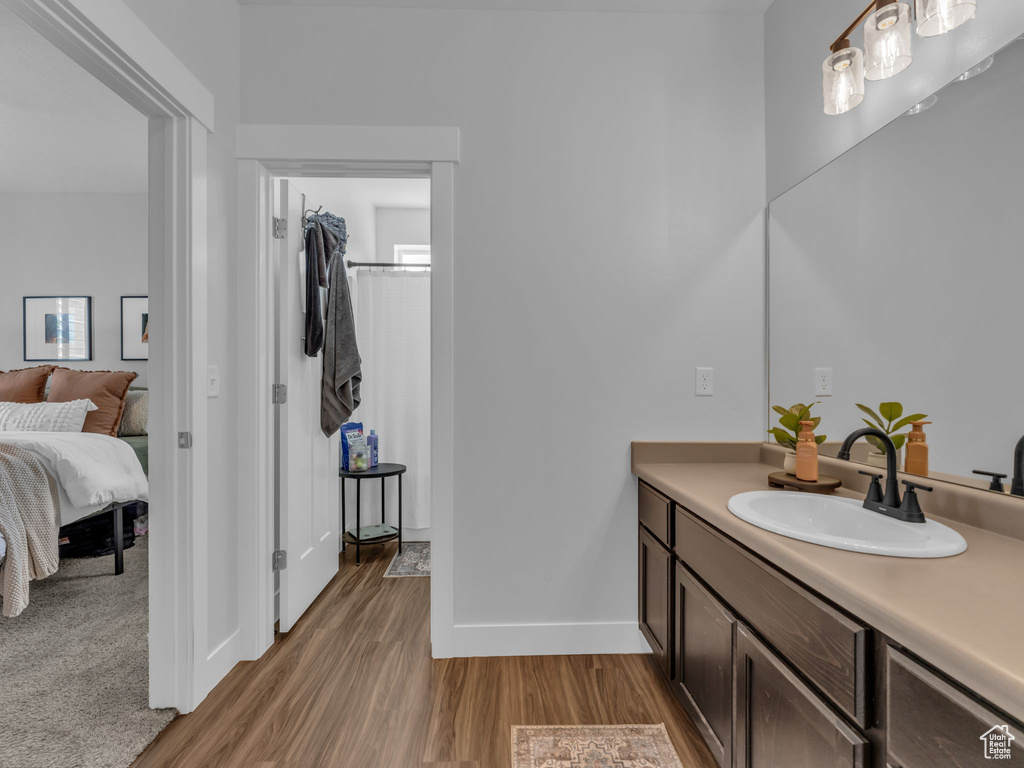 Ensuite bathroom featuring wood finished floors, vanity, and baseboards