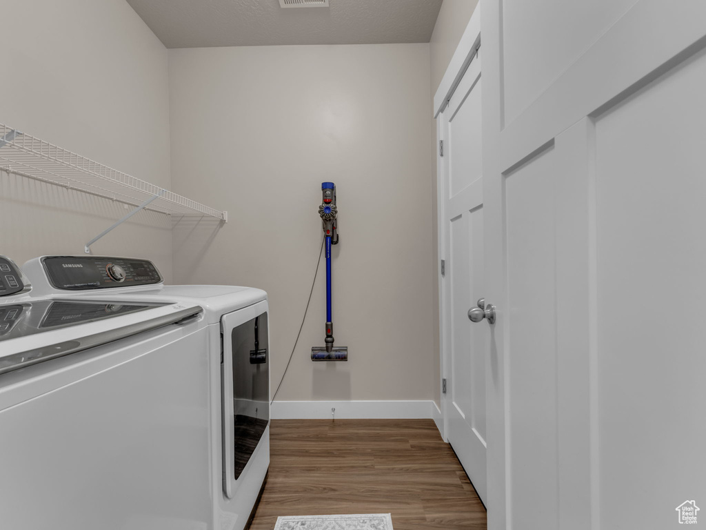 Laundry area with washing machine and dryer, wood finished floors, and baseboards