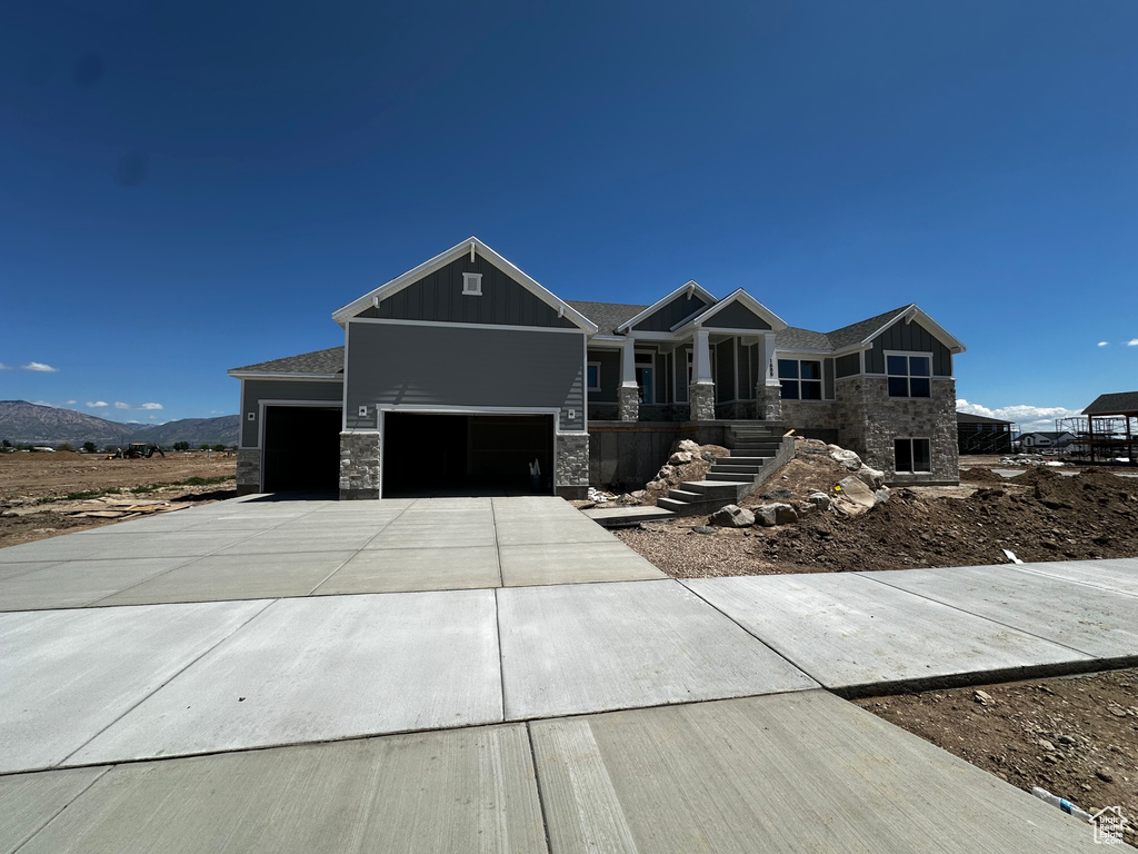 Craftsman-style home featuring board and batten siding, a garage, concrete driveway, stone siding, and a mountain view