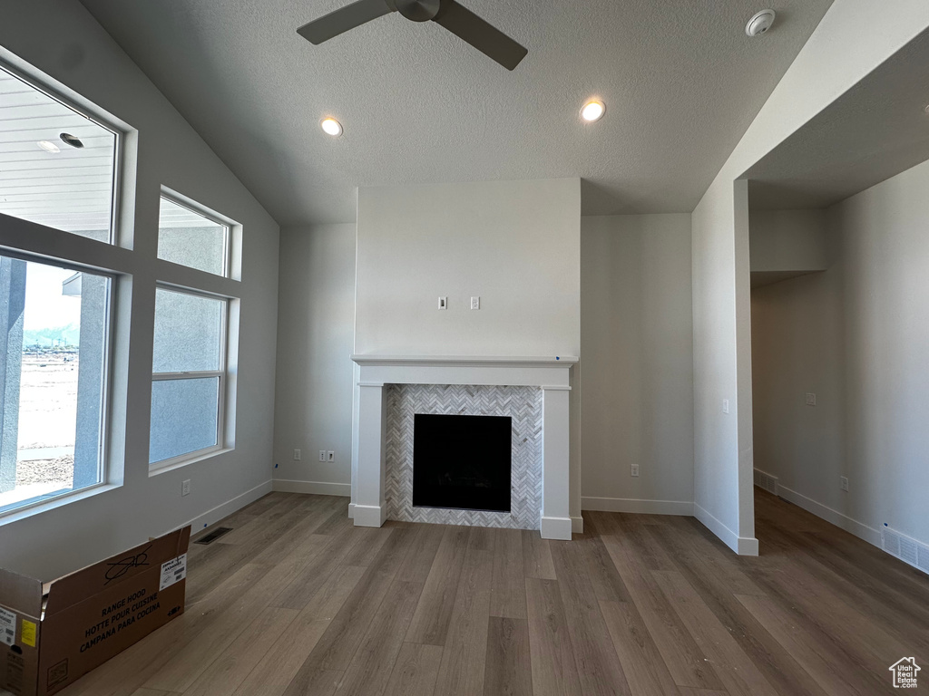 Unfurnished living room with ceiling fan, wood finished floors, a tile fireplace, a textured ceiling, and recessed lighting