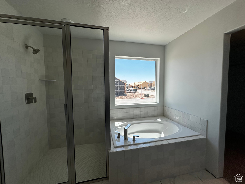 Bathroom featuring a stall shower, tile patterned floors, a bath, and a textured ceiling