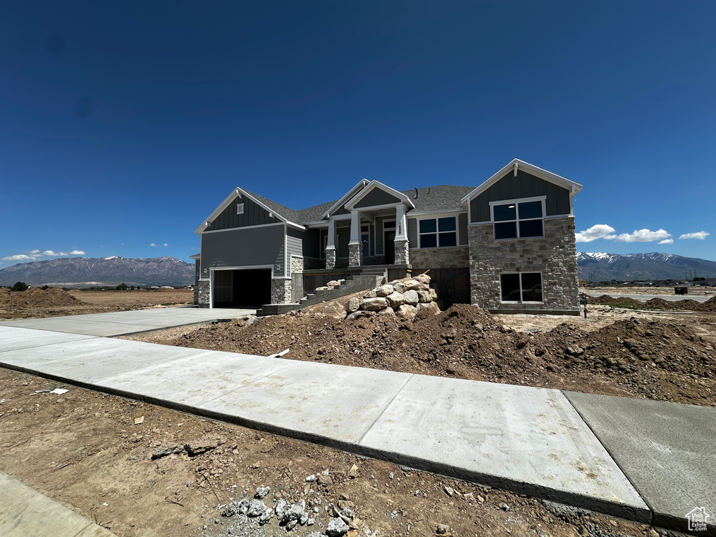 Craftsman-style house with stone siding, board and batten siding, a mountain view, a garage, and concrete driveway