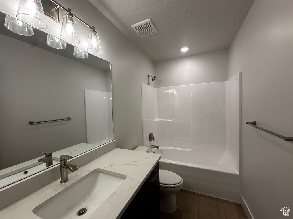 Full bath featuring toilet, wood finished floors, vanity, washtub / shower combination, and recessed lighting