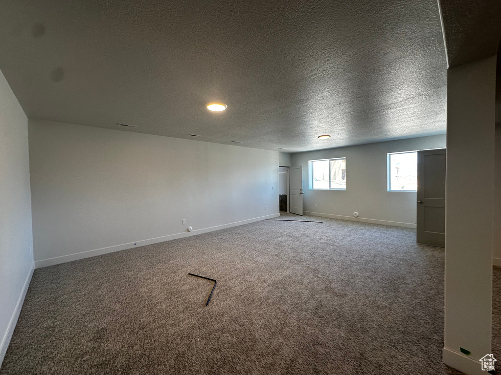 Carpeted empty room featuring baseboards, a textured ceiling, and recessed lighting