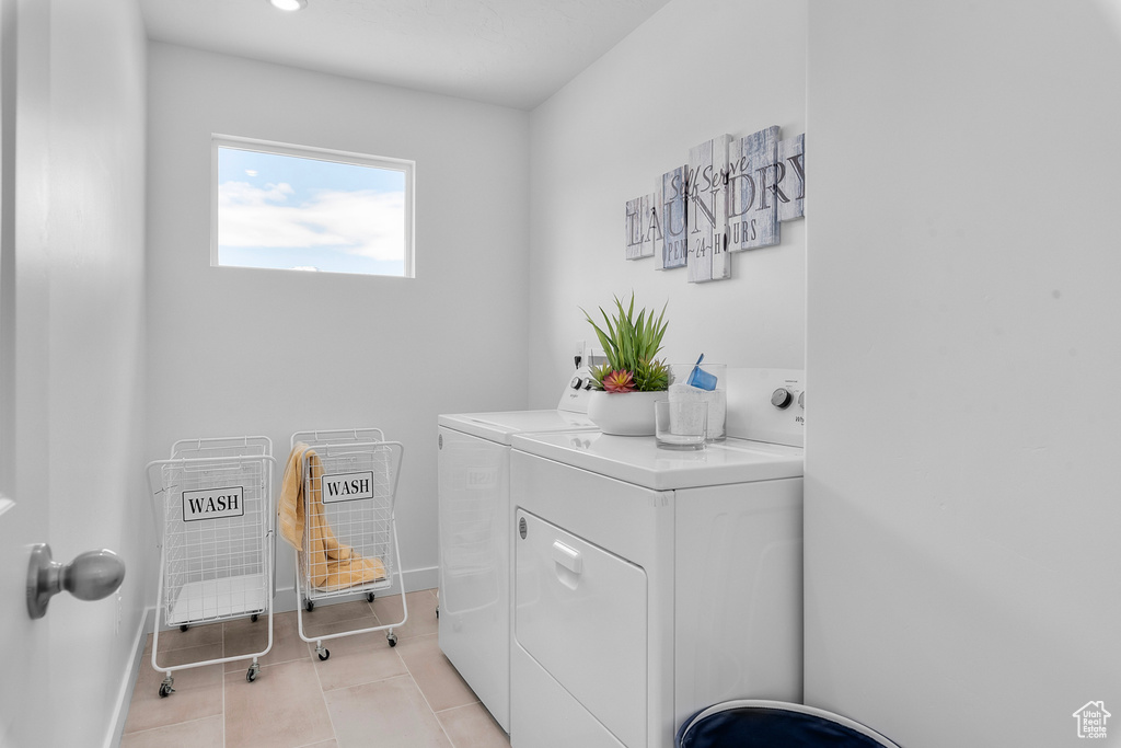 Clothes washing area with separate washer and dryer, light tile patterned flooring, and baseboards
