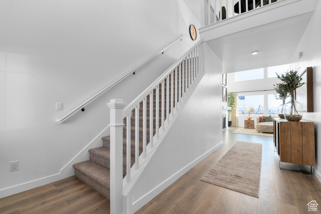 Staircase featuring a towering ceiling, wood finished floors, and baseboards