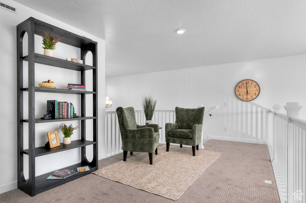 Sitting room with carpet flooring, an upstairs landing, and baseboards