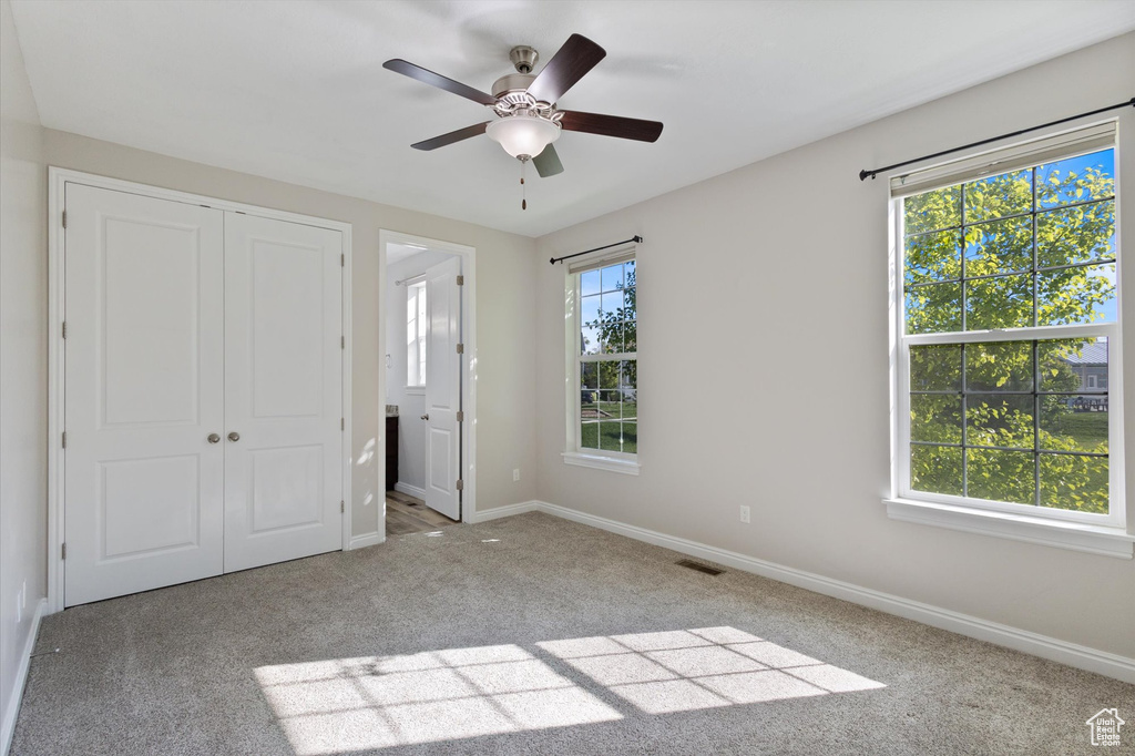 Unfurnished bedroom with carpet, a closet, baseboards, and a ceiling fan