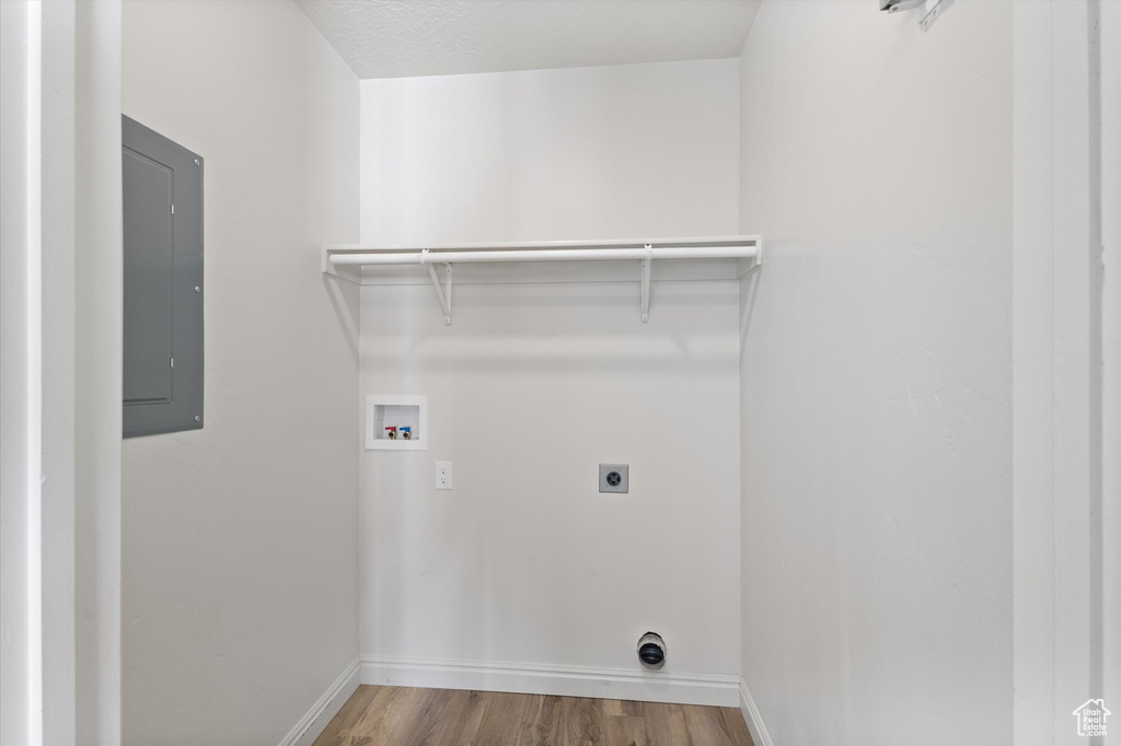 Laundry room featuring electric panel, hookup for an electric dryer, hookup for a washing machine, wood finished floors, and baseboards