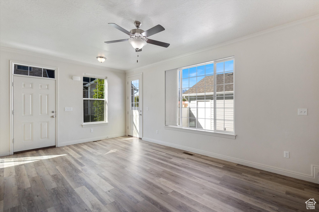 Entrance foyer featuring crown molding, a ceiling fan, wood finished floors, and baseboards