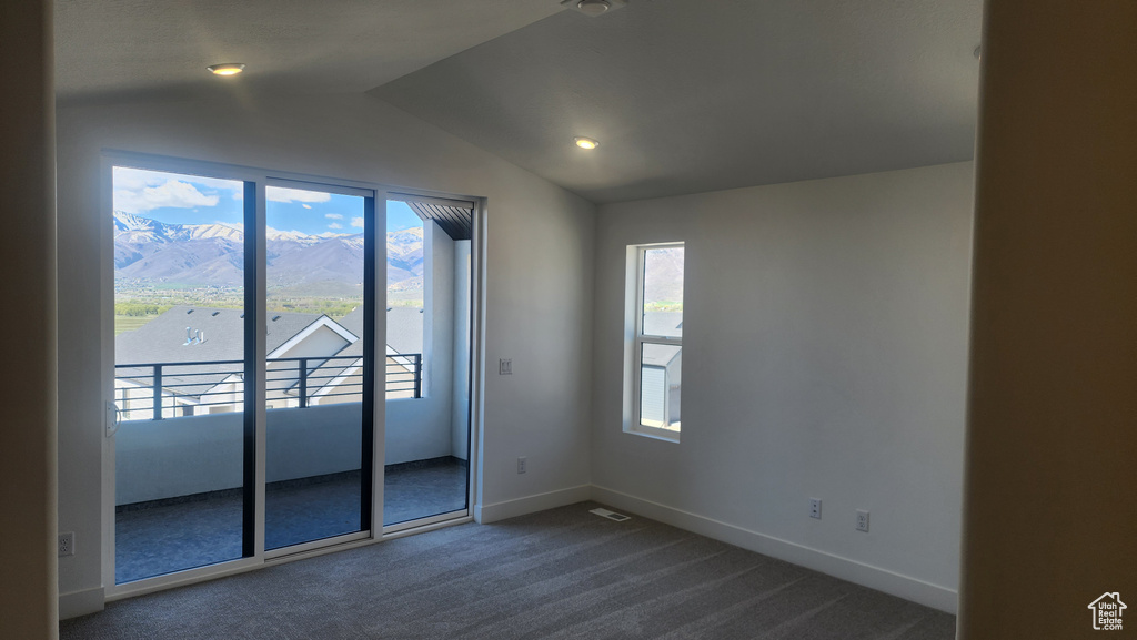 Empty room with lofted ceiling, dark carpet, baseboards, and recessed lighting