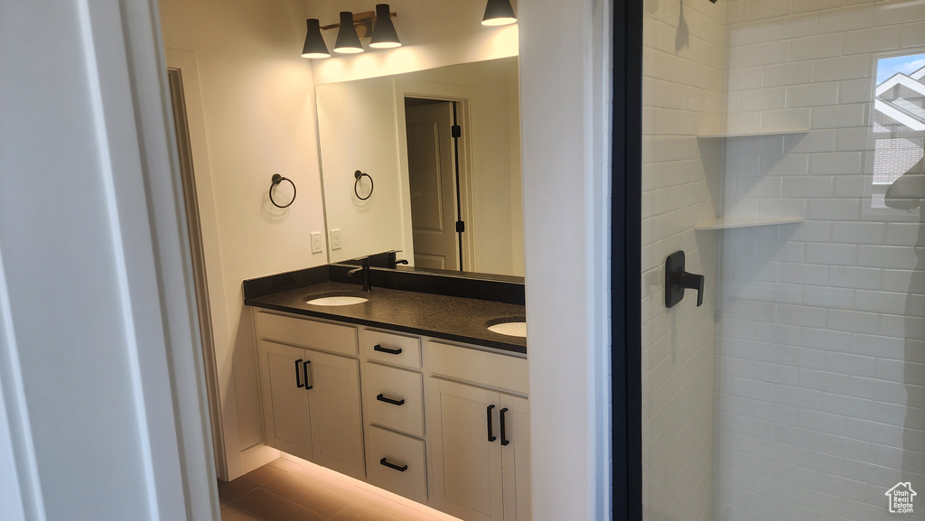 Full bathroom featuring double vanity and a tile shower