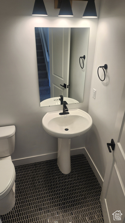 Half bath featuring toilet, baseboards, and tile patterned flooring