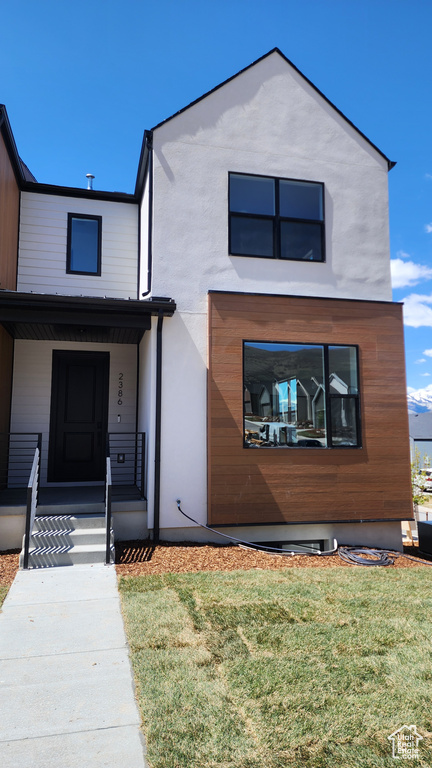 Contemporary house featuring a porch, a front yard, and stucco siding
