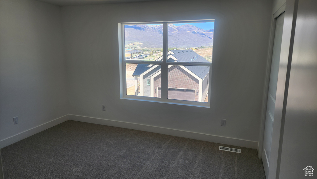 Spare room featuring dark carpet, healthy amount of natural light, and baseboards