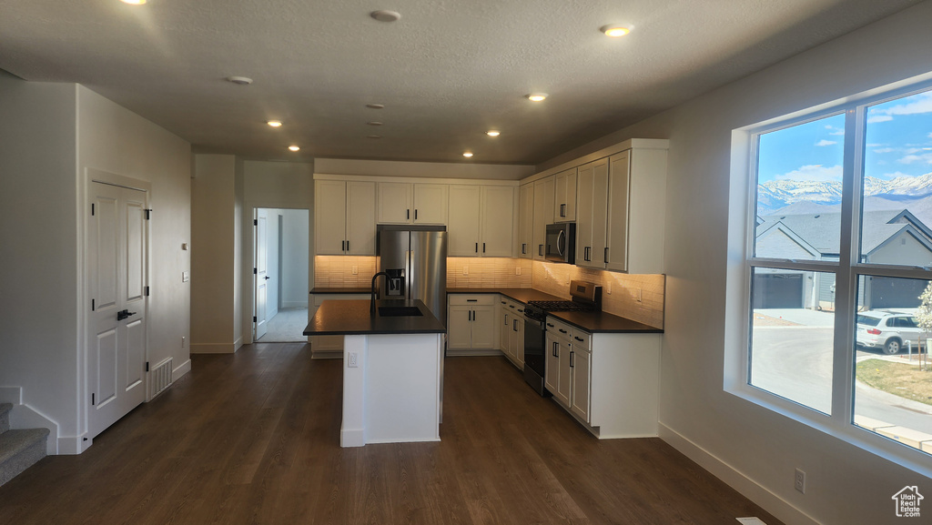 Kitchen featuring appliances with stainless steel finishes, dark countertops, backsplash, baseboards, and recessed lighting