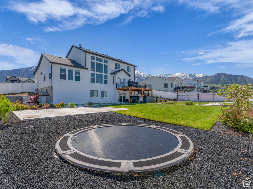 Back of property featuring a trampoline, stucco siding, and a deck with mountain view