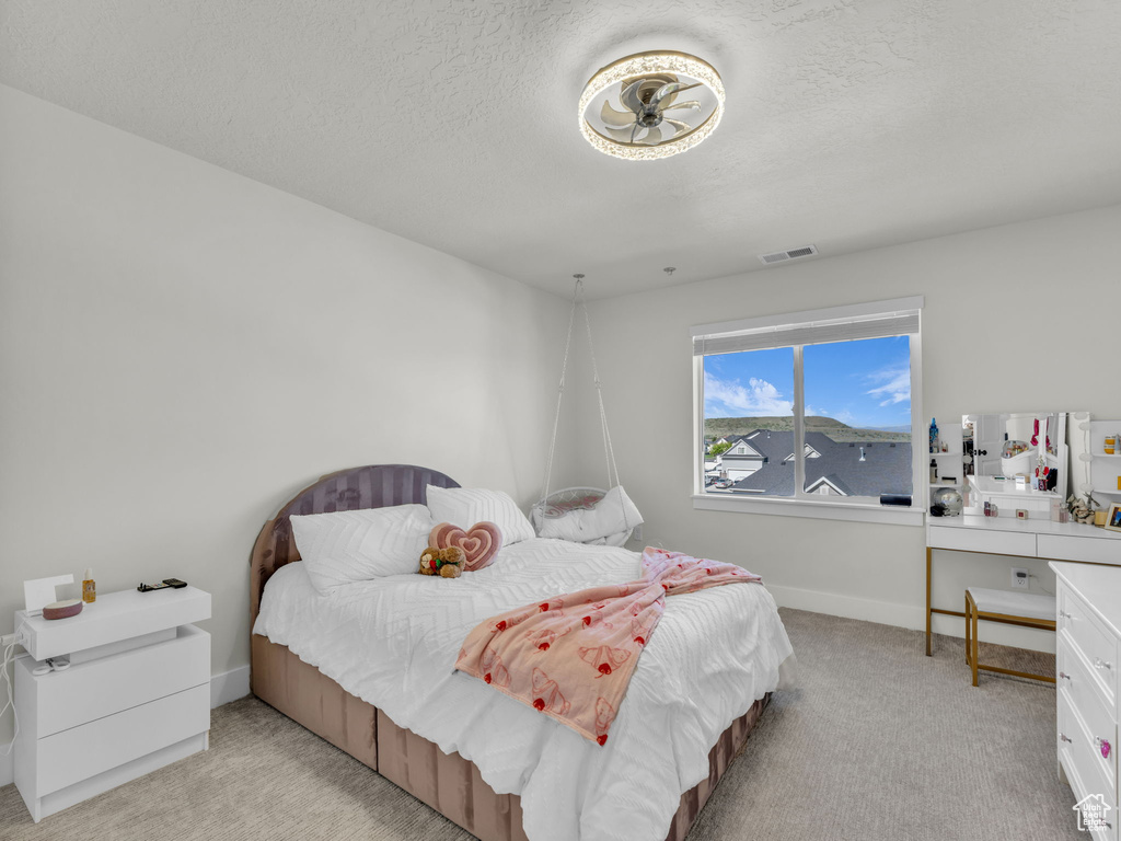 Bedroom featuring light colored carpet, a textured ceiling, and baseboards