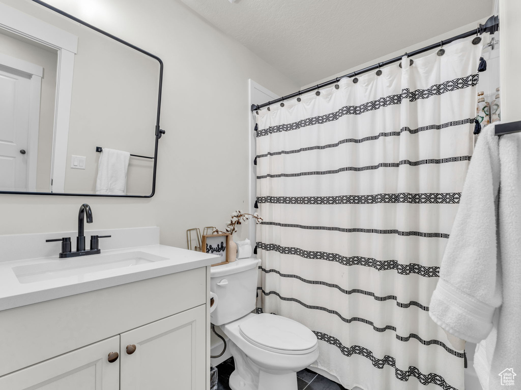 Full bath with toilet, vanity, and curtained shower