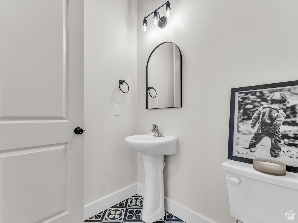 Half bath with baseboards, toilet, and a sink
