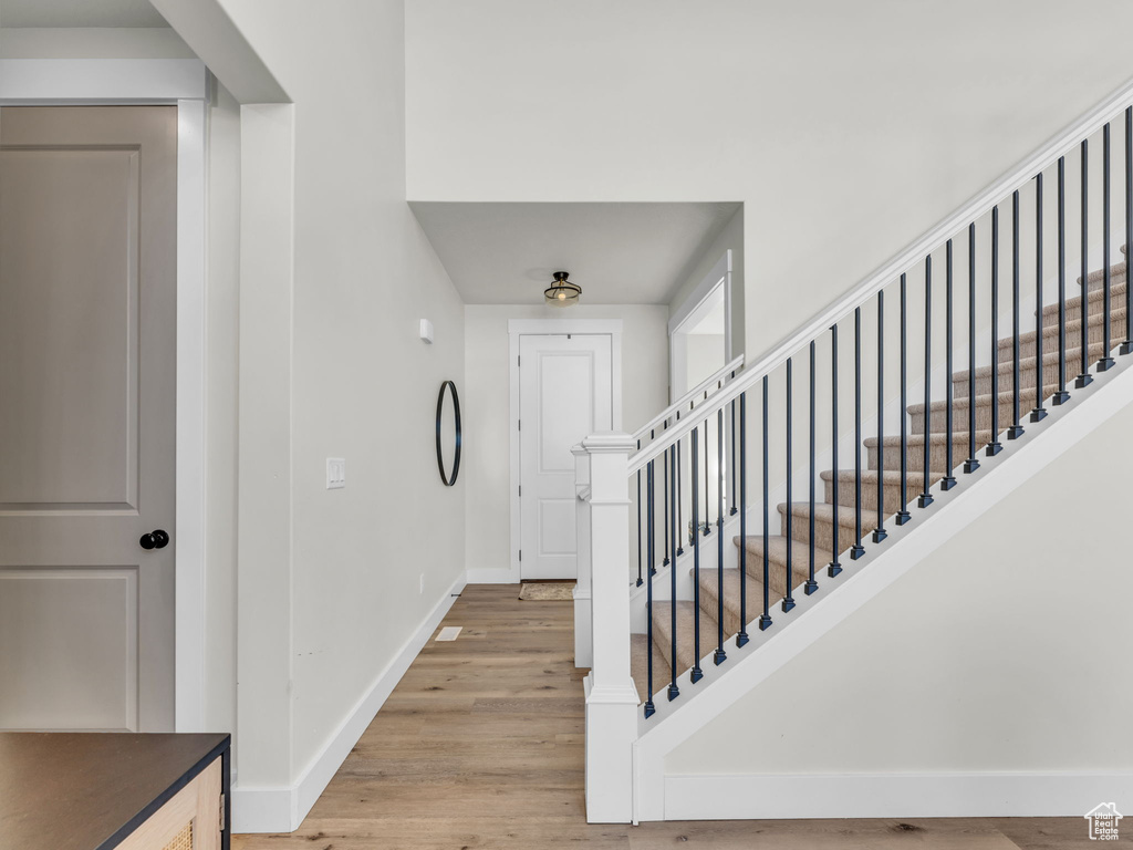 Foyer with baseboards, light wood-style floors, and stairs