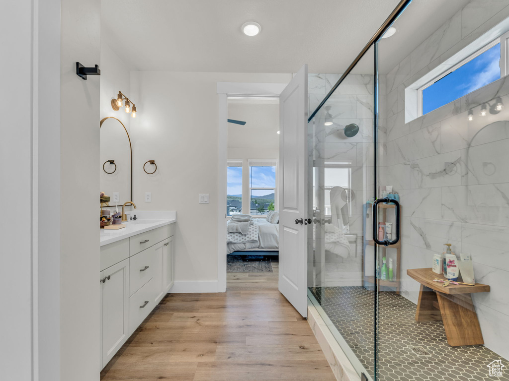 Full bath with plenty of natural light, wood finished floors, a shower stall, and connected bathroom