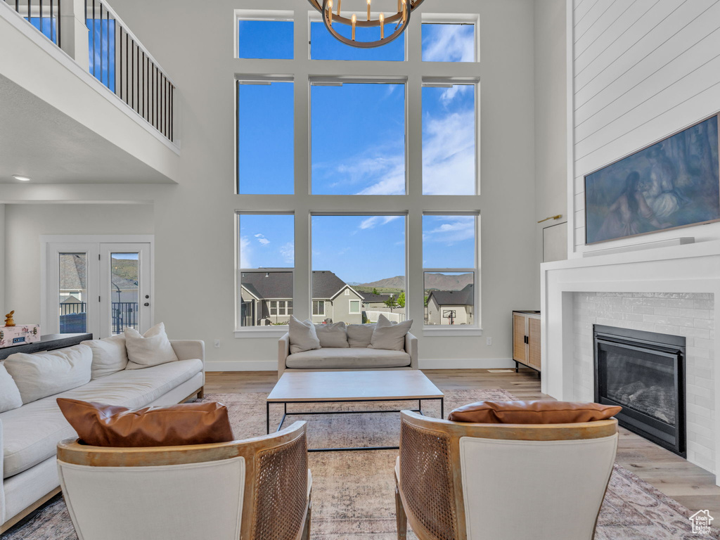 Living room featuring a high ceiling, a chandelier, light wood finished floors, and plenty of natural light