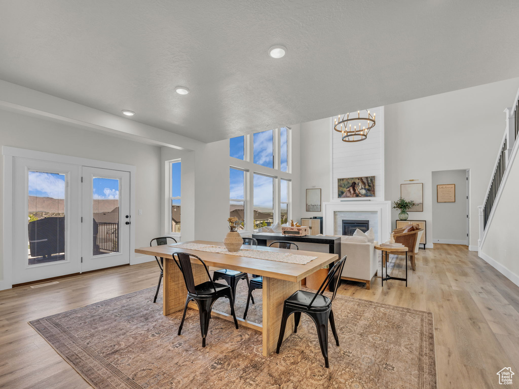Dining area with a chandelier, healthy amount of natural light, recessed lighting, a fireplace, and light wood-type flooring