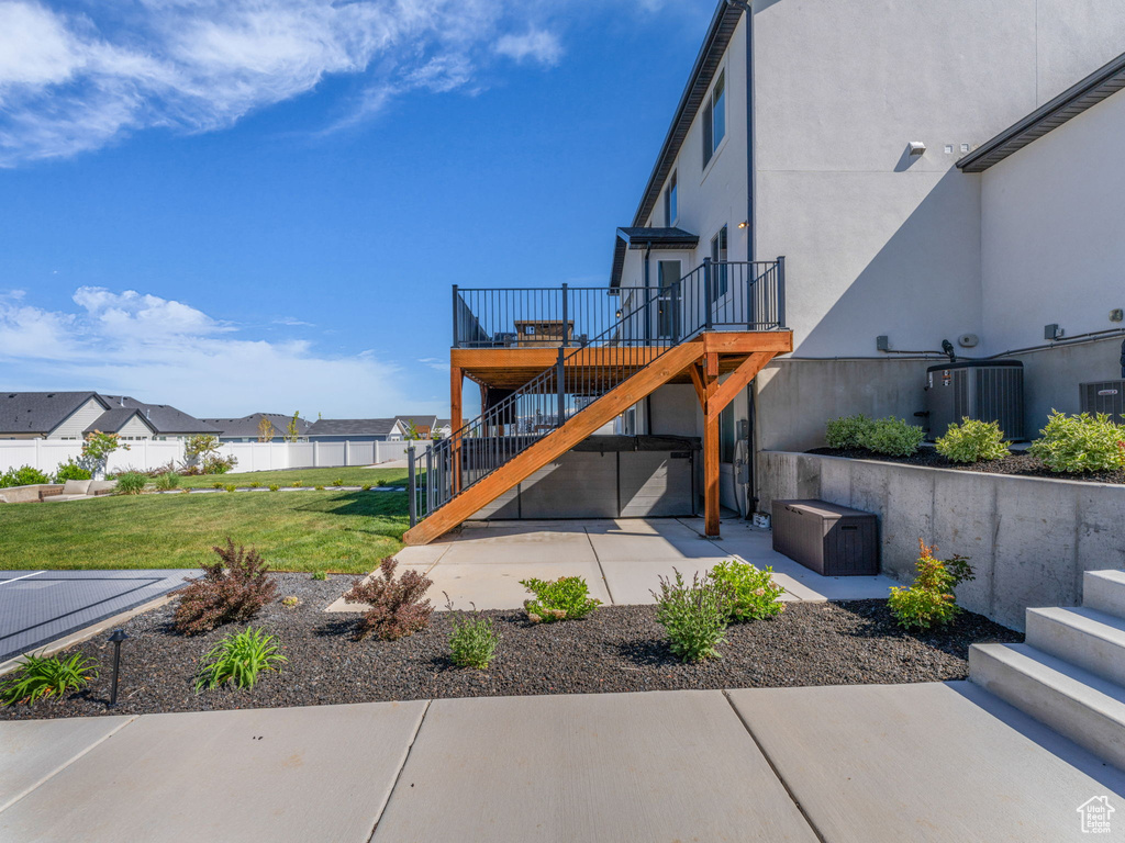 Back of property with stairs, a patio area, a wooden deck, stucco siding, and central AC unit
