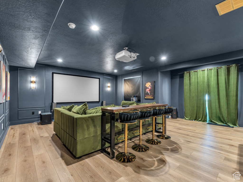 Home theater featuring a decorative wall, light wood finished floors, and recessed lighting