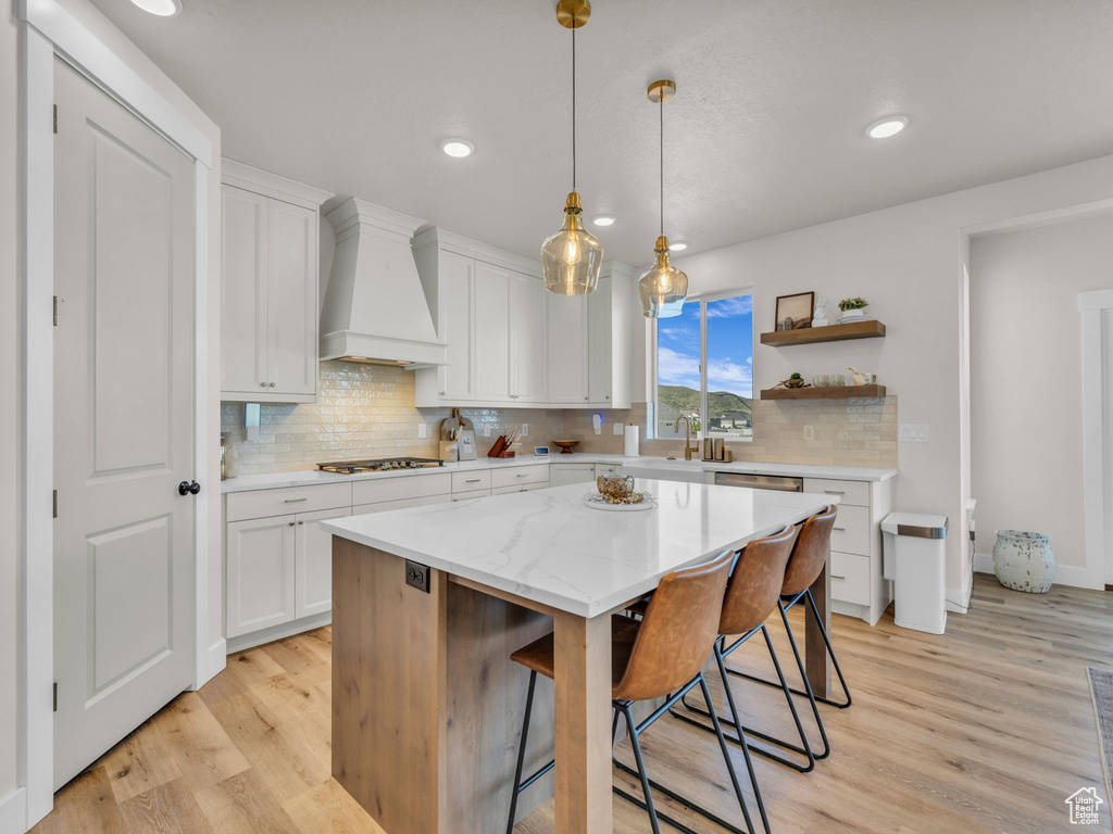 Kitchen with custom exhaust hood, light wood-type flooring, backsplash, and recessed lighting