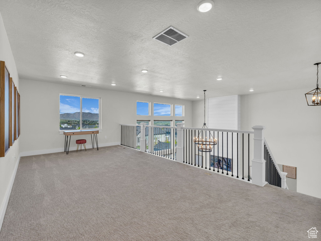 Carpeted spare room with a chandelier, recessed lighting, baseboards, and a textured ceiling