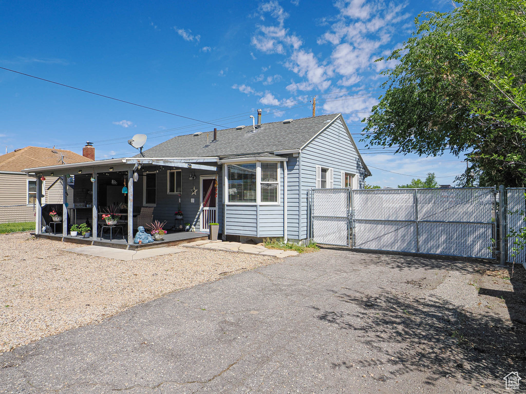 View of front of property with a gate, fence, and a shingled roof