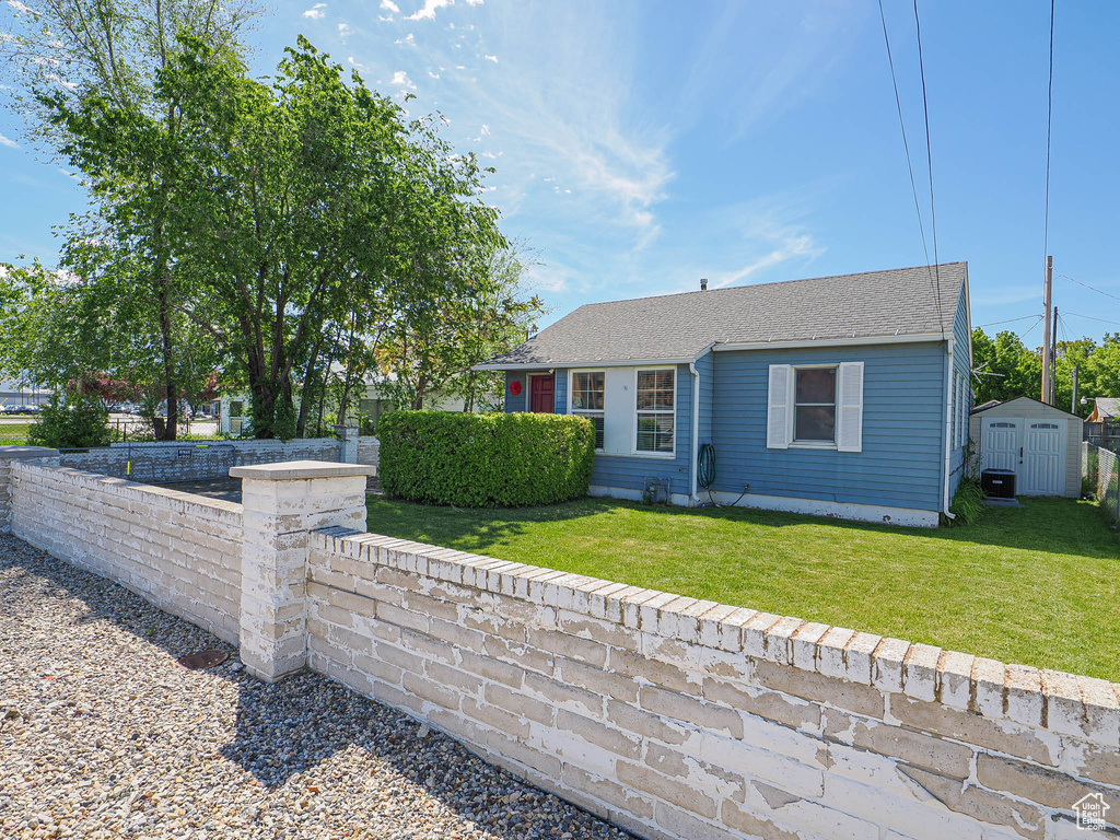 View of front of property featuring a storage shed, an outbuilding, and roof with shingles