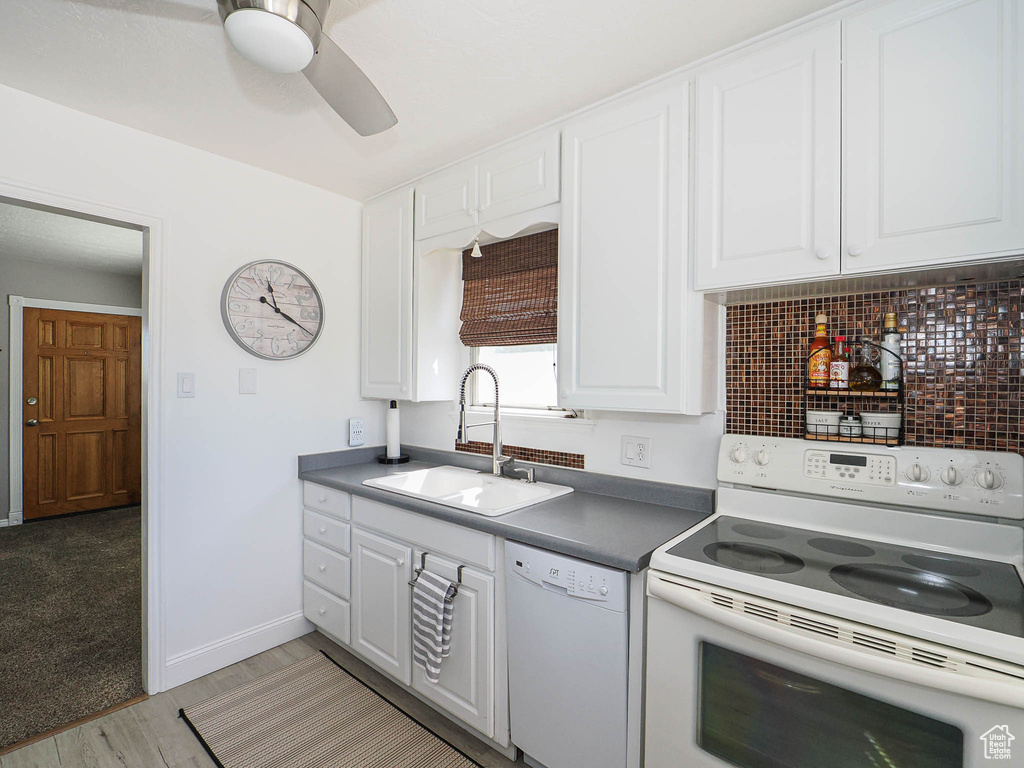 Kitchen featuring white appliances, a sink, white cabinetry, a ceiling fan, and tasteful backsplash