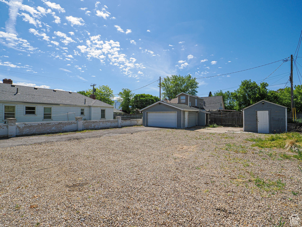 View of yard with an outbuilding, a garage, a storage unit, and fence