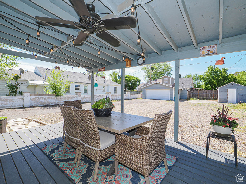 Wooden terrace with an outdoor structure, a storage shed, a fenced backyard, a ceiling fan, and outdoor dining space