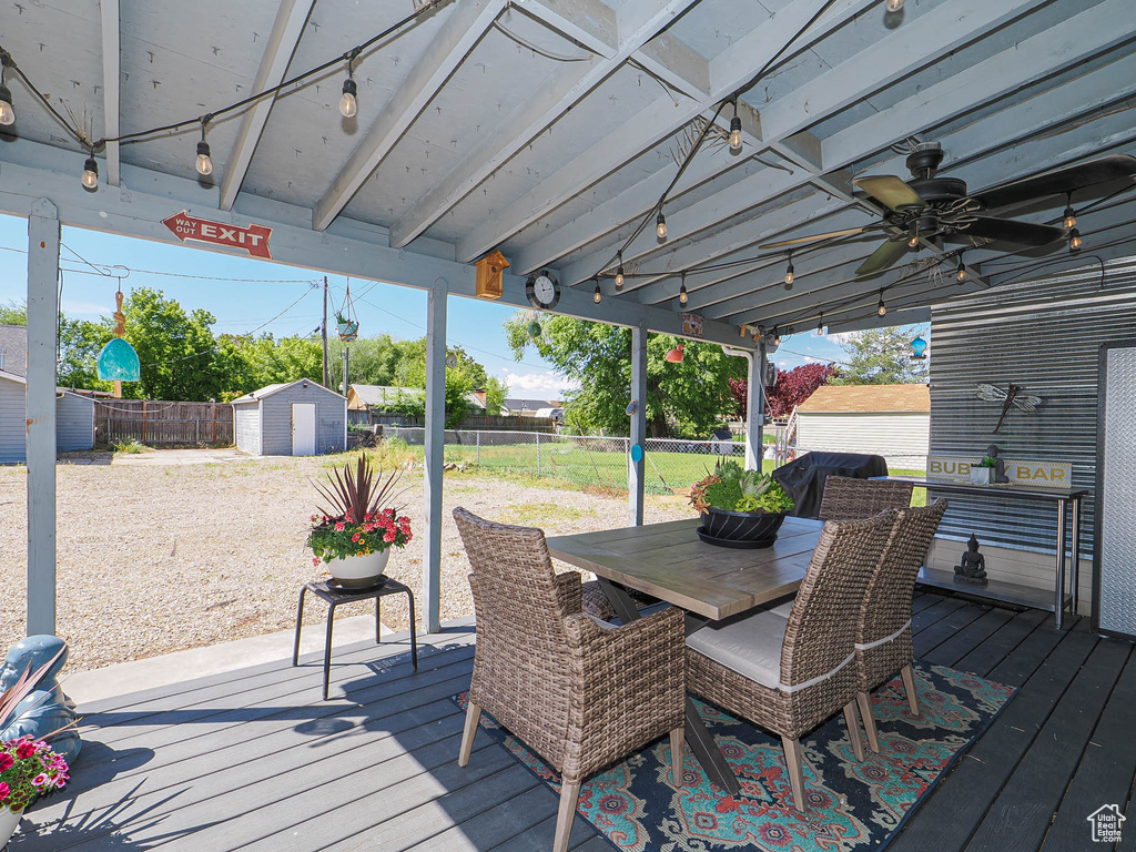 Deck with a storage unit, an outdoor structure, a fenced backyard, a ceiling fan, and outdoor dining area