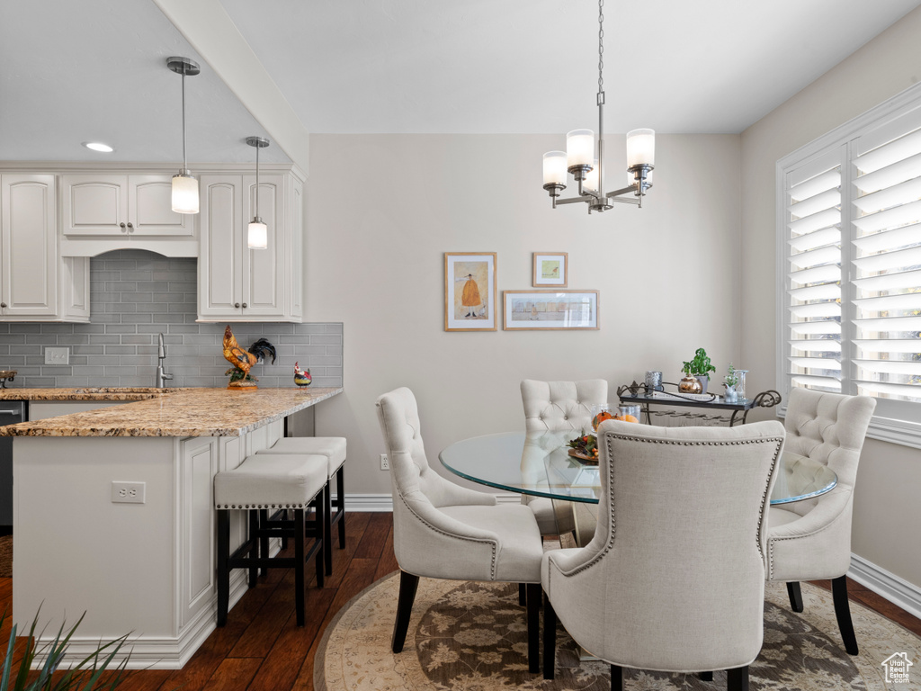 Dining room featuring dark wood-style flooring, a chandelier, and baseboards