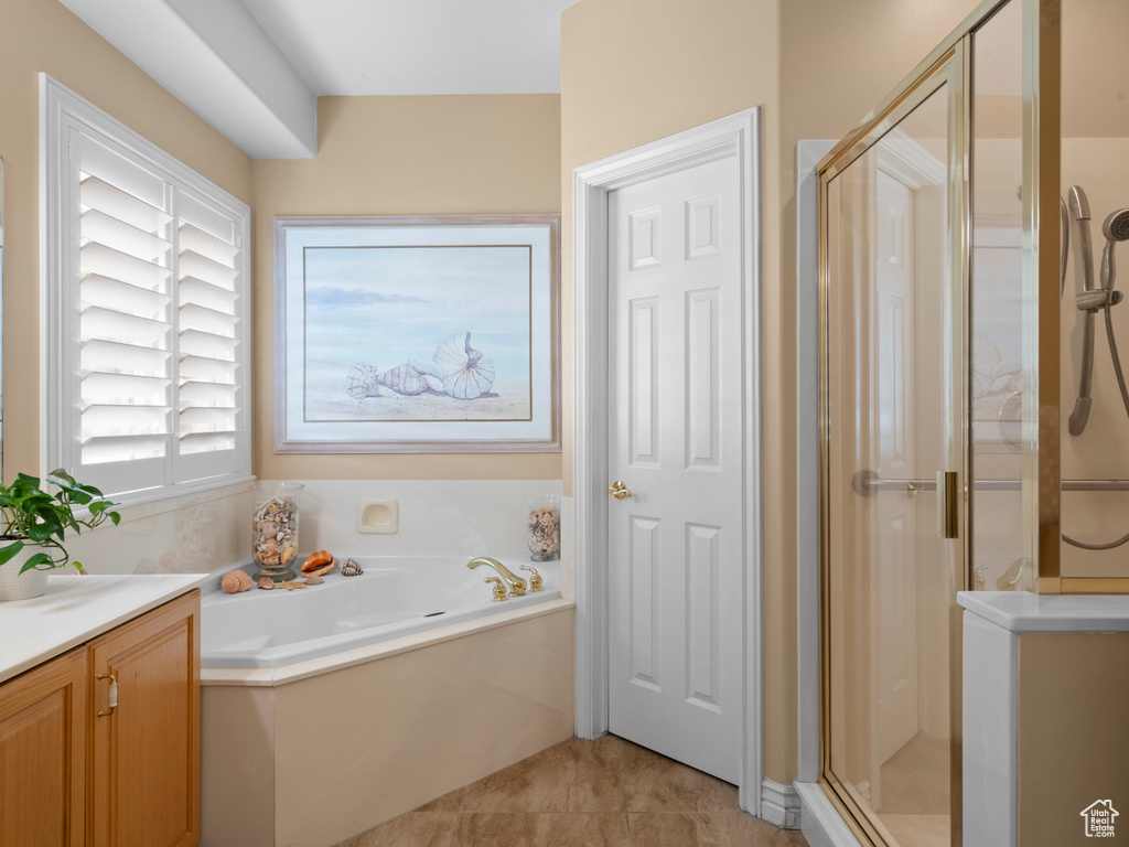 Bathroom with a shower stall, a garden tub, vanity, and tile patterned flooring