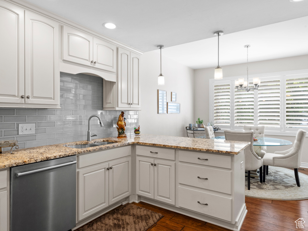 Kitchen featuring stainless steel dishwasher, a sink, a peninsula, backsplash, and dark wood-type flooring