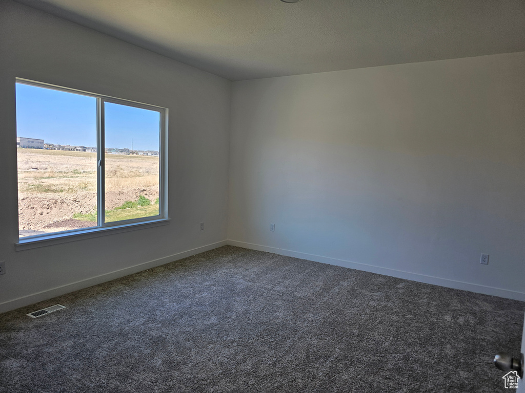 Unfurnished room with dark carpet and baseboards