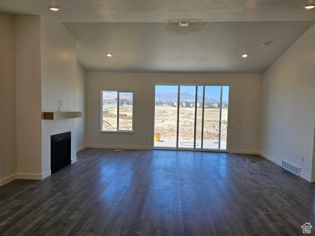Unfurnished living room featuring baseboards, a fireplace, dark wood finished floors, a mountain view, and lofted ceiling