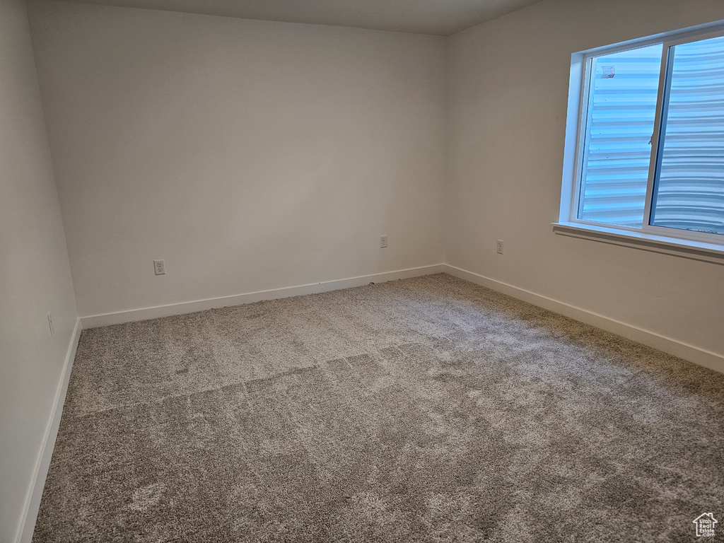 Carpeted spare room featuring baseboards