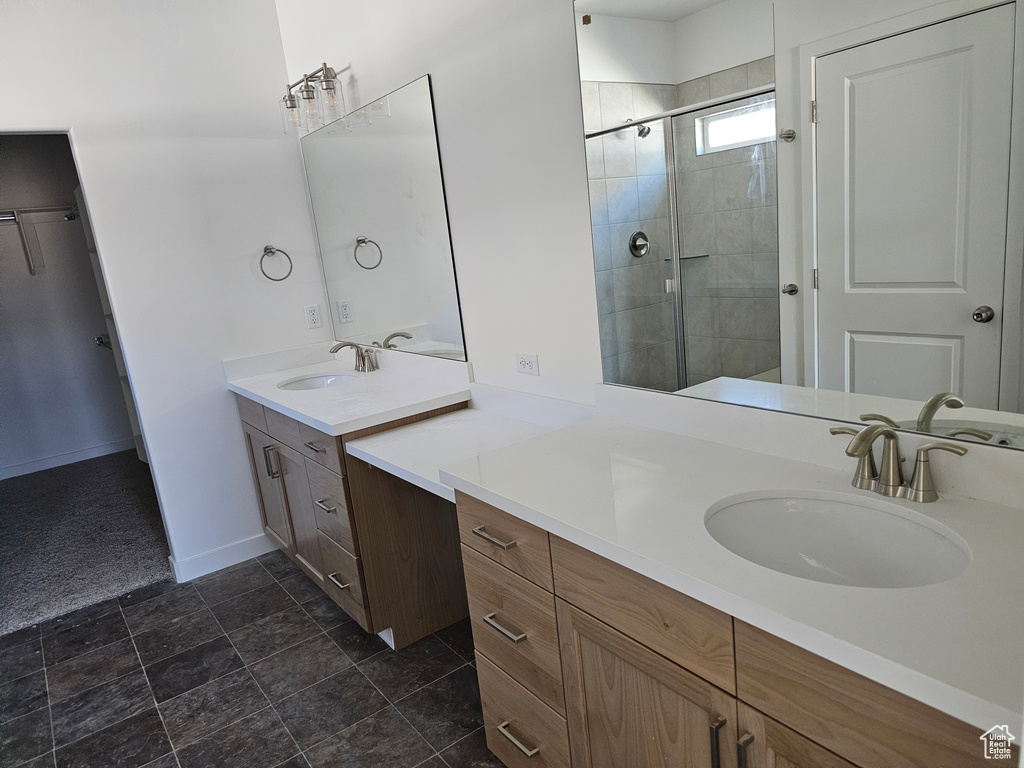 Bathroom with a stall shower, baseboards, two vanities, and stone finish flooring