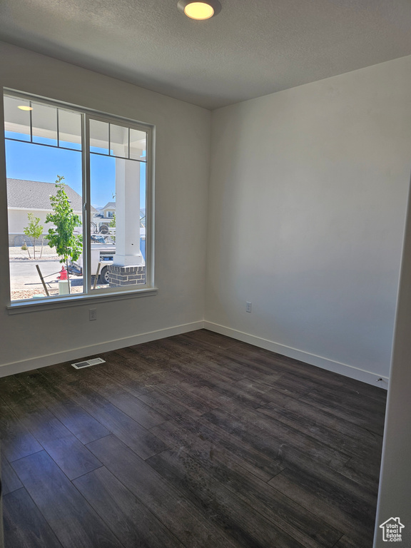 Spare room with dark wood-style flooring and baseboards