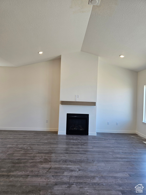 Unfurnished living room with a textured ceiling, a fireplace, dark wood-style flooring, baseboards, and recessed lighting